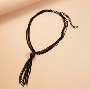 Détail du collier multi-chaînes noir avec pendentif boule et pampilles élégantes