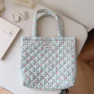 Detailed macro shot of blue checkered quilted floral cotton tote bag with brand label