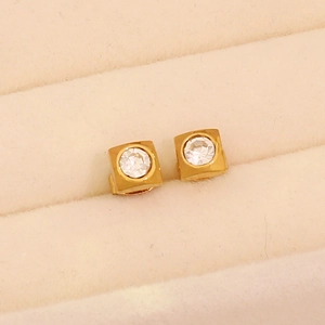 Makroaufnahme goldener quadratischer Ohrstecker mit Kristallen in beiger Schmuckschatulle