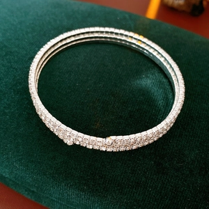 Detail of silver double-row rhinestone bangle on a luxury green velvet background