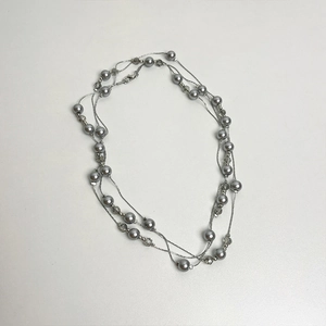 Detail of multi-layered grey pearl necklace with clear beads and silver-tone chains