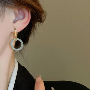 Gros plan d'un mannequin portant des boucles d'oreilles dorées avec jade et zircon
