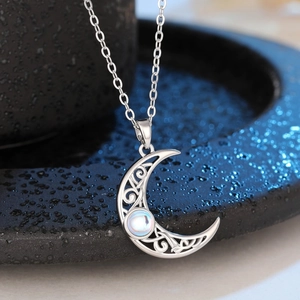 Detailed view of silver moon pendant with moonstone and intricate filigree design