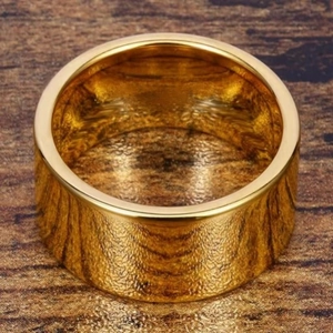 Macro di anello in oro lucido largo 12mm su superficie in legno che mostra la trama metallica