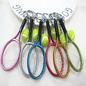 Detailed close-up of six colorful tennis racket keychain pendants on a white plate