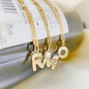 18k gold plated stainless steel letter pendant necklace featuring sunburst texture details