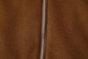 Macro view of metallic silver zipper on high-quality brown suede fabric jacket