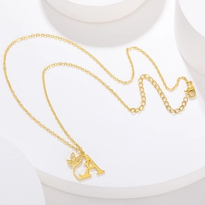 Macro detail of gold letter A pendant with artistic side profile and leaf design