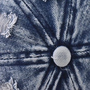 Macro detail of washed denim baseball cap top with distressed frayed edges and stitching