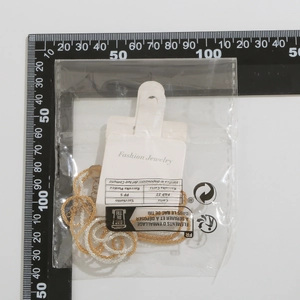 Detail of layered gold and silver chain necklaces with packaging and measurement scale