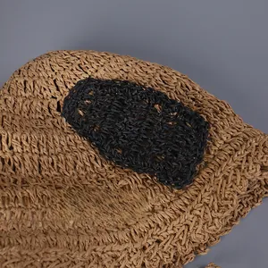 Detail of hand-woven straw hat showing black knit ear decorations and durable texture