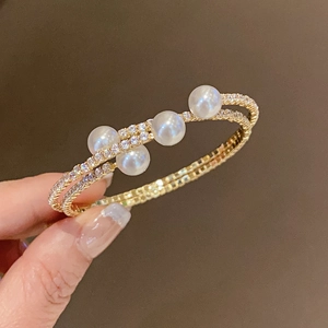 Macro shot of double-layer gold pearl bracelet with micro-paved rhinestones on model hand