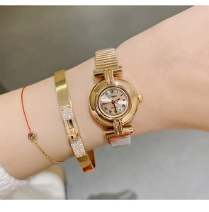 Close-up of gold DINIMI ladies watch with Roman numerals and stacked bracelets