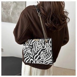 Detailed view of black and white zebra print bag with gold chain and woven texture