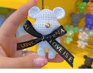 Detailed close-up of white resin bear keychain featuring a Love Is Eternal ribbon bow