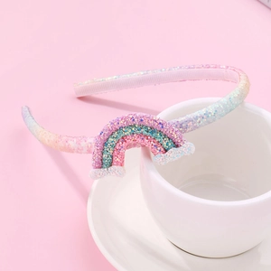 Sparkly rainbow headband for girls with pink glitter finish on a white saucer