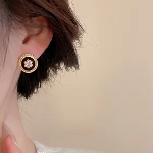 Detail of elegant gold-rimmed red pearl flower earrings on a model in vintage style