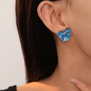 Elegant blue floral stud earrings with gold trim and crystal center on model