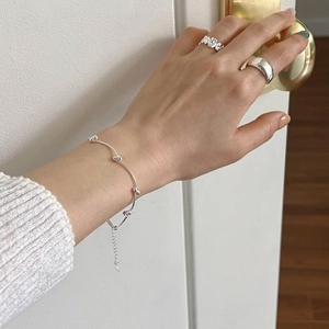 Detailed view of S925 sterling silver beaded bracelet and minimalist rings on a hand