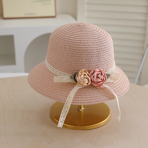 Close-up of pink straw hat featuring delicate lace ribbon and floral fabric rose details
