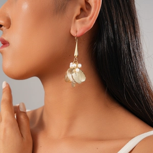 Close-up of gold drop earrings with pearls and brushed metal petals on model