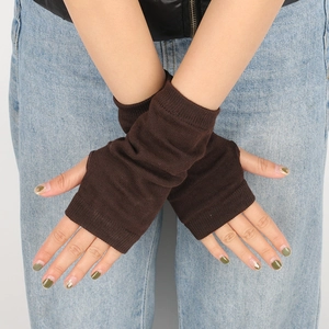 Detailed knit texture of dark brown fingerless arm warmers on a denim background
