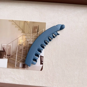 Detailed macro view of matte blue banana hair clip with secure teeth and sphere detail
