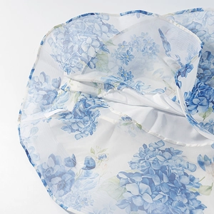 Detail of blue hydrangea floral print on white mesh fabric of a stylish dress