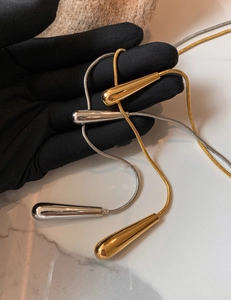 Detailed close-up of water drop pendants in gold and silver with snake bone chains