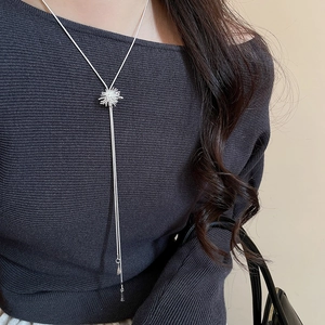 Detailed view of silver zircon starburst pendant necklace with fine snake chain on a model