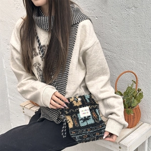 Detailed side view of a plush knit crossbody bag with ethnic patterns and cord strap