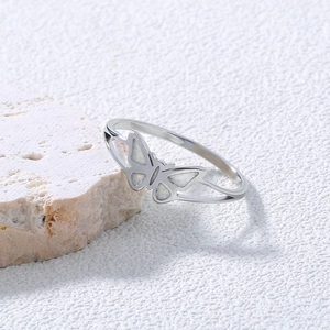 Macro detail of silver stainless steel butterfly ring resting on a textured natural stone
