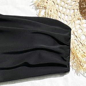 Close-up of black ruched high-elastic swimwear fabric showing detailed texture and stitching