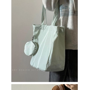 Detail of mint green nylon tote bag featuring a matching round detachable mini coin pouch