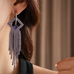 Close-up of geometric lavender crystal fringe earrings on model with sparkling tassels