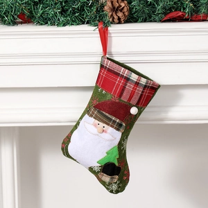 Green Christmas stocking with Santa Claus embroidery and red plaid cuff hanging on mantel