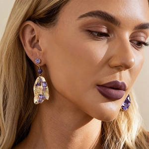 Bohemian gold-tone earrings with purple crystals and rhinestones shown on model