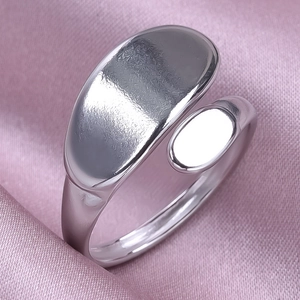 Close-up of polished stainless steel curved open ring on a pink satin fabric background