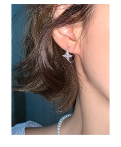 Detailed close-up of a silver star hoop earring with sparkling zircons on a model ear