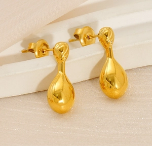 Close-up of golden teardrop earrings with polished mirror finish on silk background