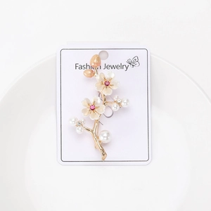 Close-up of elegant plum blossom brooch with white petals and pearls on display