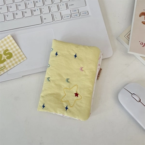 Macro shot of embroidered star patterns on a soft yellow quilted passport holder bag