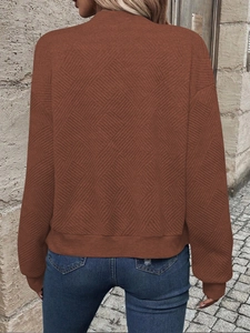 Close-up of brown long sleeve jacket featuring geometric quilted texture and ribbed cuffs