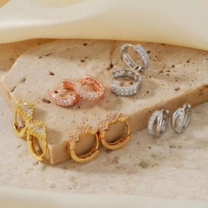 Elegant zircon hoop earrings in gold, silver and rose gold on a stone tray