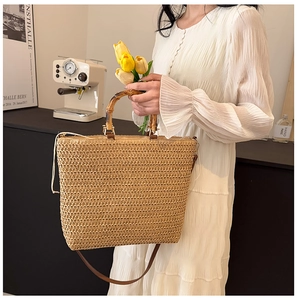 Macro detail of hand-woven straw tote bag with natural bamboo handle and leather strap