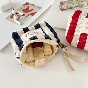 Close-up of small striped canvas pouch with smooth zipper and colorful cloth label