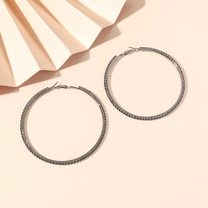 Close-up of 8cm oversized hoop earrings with dark rhinestones on light pink background