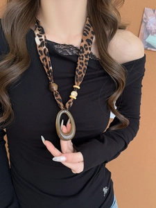 Detailed view of large brown resin pendant and leopard print fabric cord necklace