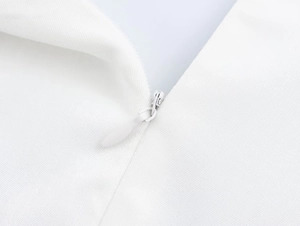 Detailed close-up of a high-quality invisible zipper on a white sleeveless mini dress