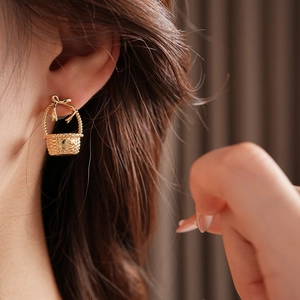 Close-up of gold bow basket stud earring with woven texture shown on a female model